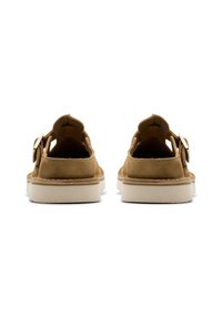 Καφέ σουέτ σανδάλια με κλειστή φτέρνα, ανοιχτά δάχτυλα και λευκή ελαστική σόλα. Διαθέτουν κυκλικό χρυσό πόμολο στη μία πλευρά.