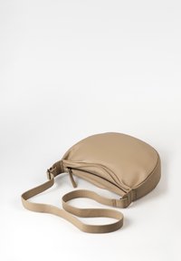 Borsa rotonda in pelle beige con una texture liscia, chiusura con zip e tracolla piatta. Progettata per essere indossata a tracolla o sulla spalla.
