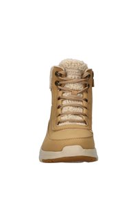 Botín de tobillo impermeable color marrón con forro de felpa texturizada, cordones beige y suela de goma. Presenta un collar acolchado y un logotipo en la lengüeta.