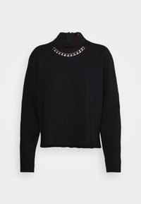 Pull court noir à manches longues avec col montant, orné d'un détail en chaîne de couleur argentée traversant le col.