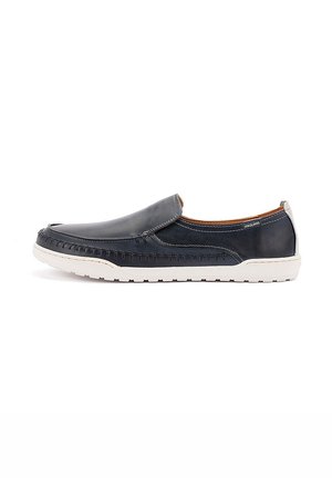 Chaussure à enfiler en cuir bleu marine avec semelle en caoutchouc blanche, détails cousus et petit talon, conçue pour un usage décontracté.