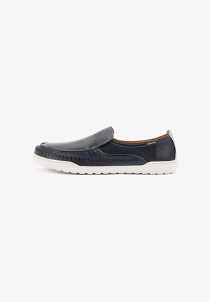 Chaussure à enfiler en cuir bleu marine avec semelle en caoutchouc blanche, détails cousus et petit talon, conçue pour un usage décontracté.