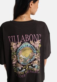 Μαύρο υπερμεγέθες t-shirt με πολύχρωμα λουλουδάτα γραφικά, μοτίβα ήλιου και κυμάτων και το κείμενο "BILLABONG" σε ροζ. Υλικό από βαμβάκι.