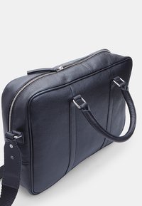 Mørkeblå læder aktetaske med dobbelte håndtag, lynlås lukning og tekstureret overflade. Har sølv hardware og minimalistisk design.