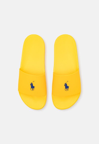 Chinelas amarelas em material sintético, com uma palmilha texturizada e um logótipo em silhueta azul marinho na alça.