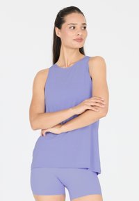 Top atletico senza maniche di colore viola con scollatura rotonda e vestibilità ampia, abbinato a pantaloni corti viola coordinati, realizzati in un tessuto liscio e elasticizzato.