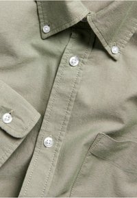 Olijfgroene overhemd van textuurstof, met een button-down kraag, witte knopen en een borstzak.