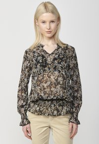 Blusa nera floreale con maniche lunghe, scollo a V, orlo e polsini rifiniti con volant, realizzata in un materiale trasparente con intricate fantasie botaniche in oro e bianco.