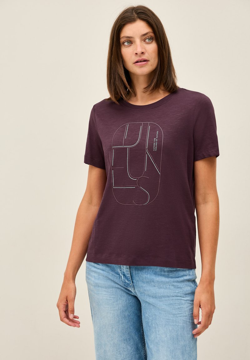 Lyhythihainen violetti t-paita, joka on valmistettu pehmeästä kankaasta. Tässä paidassa on erottuva graafinen kuviointi vastakkaisissa väreissä. Rento malli, jossa on pyöreä kaula-aukko.