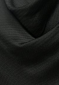 Tecido preto com padrão fino e texturizado; superfície lisa com brilho subtil; dobrado, exibe forma fluida e queda suave.