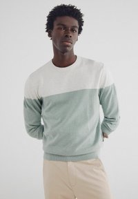 Leichter Strickpullover in Mintgrün und Cremeweiß, mit Rundhalsausschnitt, langen Ärmeln und gerippten Bündchen. Glatte Textur, lässige Passform.