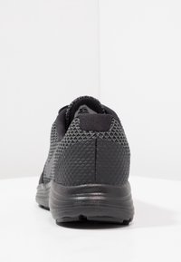 Scarpa sportiva nera con tomaia in rete testurizzata, collare imbottito e suola nera liscia. Design minimalista, focalizzato sulle prestazioni e sul comfort.