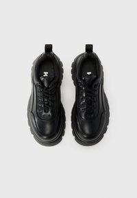 Sorte lædersneakers med rund tå og tyk gummisål. Har snørelukning og en træksløjfe. Teksturerede detaljer på overdelen.