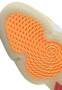 Semelle de chaussure avec bord extérieur beige translucide et grip texturé orange présentant des indentations ovales allongées et un motif circulaire près du talon.