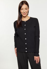 Černý pletený cardigan s texturovaným vzorem, kulatým výstřihem a zapínáním na knoflíky s bledými knoflíky. Dlouhé rukávy, žebrované manžety.