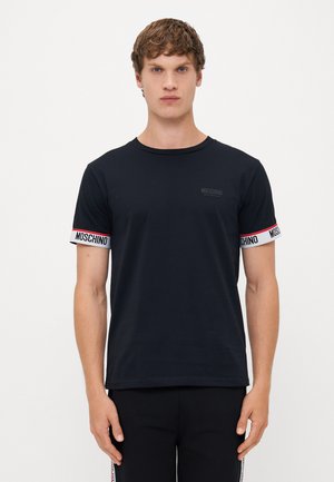 Crna pamučna majica kratkih rukava s crvenim i bijelim „MOSCHINO“ logotipom. Lagano prilagođen dizajn, okrugli izrez, minimalno brendiranje na prsima.