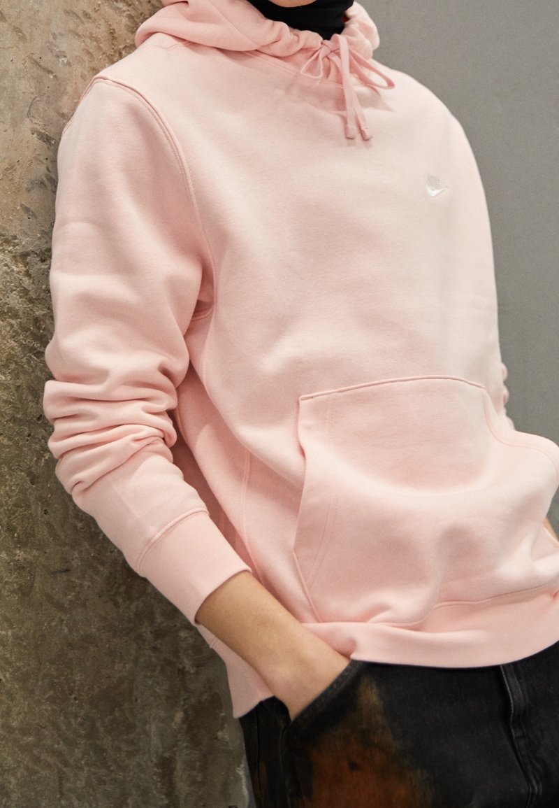 Rosa sweatshirt gjord av mjukt tyg, med en framficka och dragsko-huva. Märkbar logotyp placerad på bröstet. Avslappnad passform.