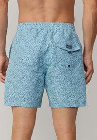 Pantaloni da bagno azzurri chiari con motivo a foglie, vita elasticizzata e tasca posteriore con chiusura a bottone. Realizzati in tessuto traspirante.