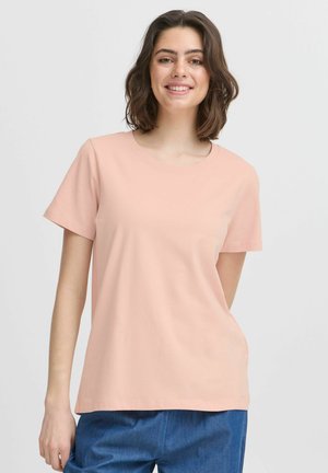 Light pink short-sleeve T-shirt made of soft fabric with a round neckline. The fit is relaxed, paired with blue denim pants.