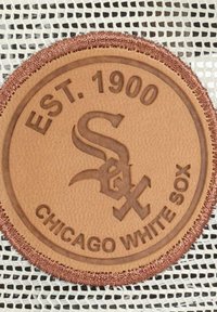 Braunes Lederpatch in runder Form mit geprägtem Text "EST. 1900" und "CHICAGO WHITE SOX", einem Logo in der Mitte und braunem Stich.