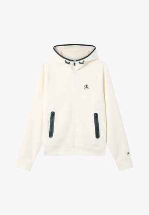 Ecru bluza z kapturem zapinana na zamek z czarnymi kieszeniami na zamek, regulowanymi sznurkami kaptura oraz małymi logo Champion na piersi i mankiecie rękawa.