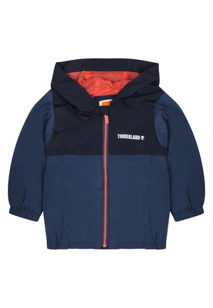 Veste enfant bleu marine avec capuche, doublure orange et fermeture éclair à l'avant. Présente des poignets élastiques et le logo Timberland sur la poitrine.