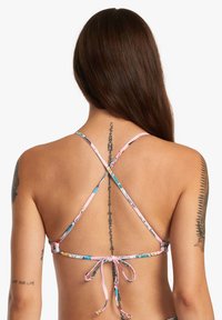 Haut de bikini multicolore avec de fines bretelles croisées et une fermeture à nouer. Motif floral sur un tissu doux, révélant des détails de tatouage dans le dos.