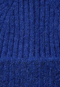 Tessuto di maglia blu che mostra una trama a coste con fibre visibili, creando un aspetto morbido e caldo. Nessun motivo o dettaglio aggiuntivo.