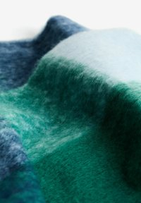 Wool blanket in gradient hues of dark blue, green, and light blue, featuring a soft, textured surface with a smooth, flowing design.