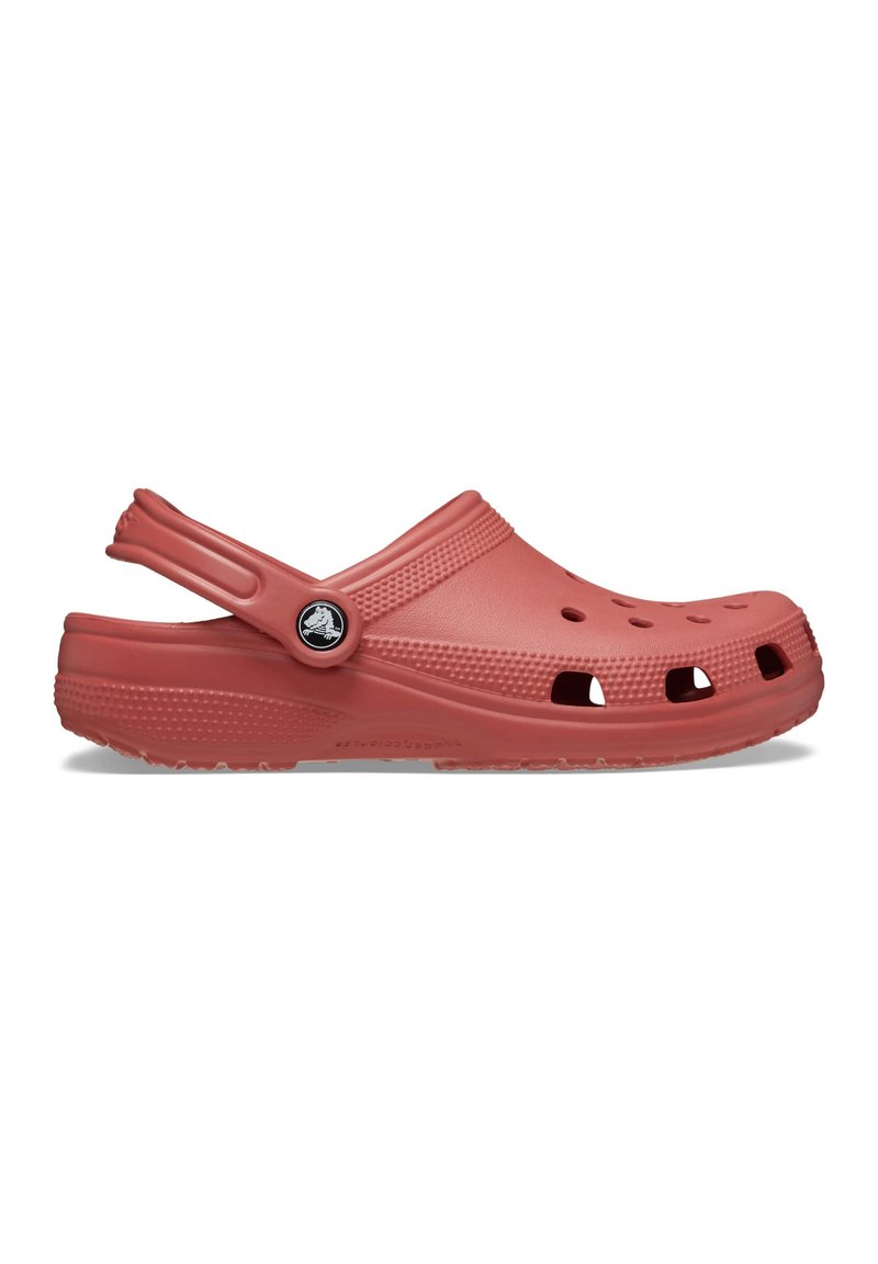 Rote Kunststoff-Clogs mit Belüftungsöffnungen, Riemen an der Rückseite, strukturierten Oberflächen und einem kreisförmigen Logo-Akzent an der Seite. Leicht und langlebig im Design.