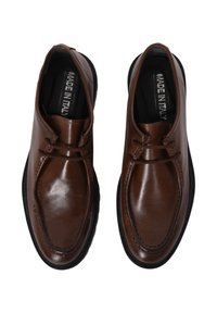 Scarpe in pelle marrone con texture liscia, dettagli dei lacci, punte arrotondate e suola in gomma nera. L'etichetta interna riporta "MADE IN ITALY."