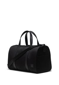 Crna torba za teret napravljena od izdržljive tkanine. Ima dva ručka, podesivu naramenicu, zatvaranje na patentni zatvarač i prednji džep.