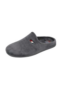 Zapatilla de felpa gris tipo pantufla, con la puntera cerrada y el talón abierto, y un pequeño logo rectangular en rojo, blanco y negro en la parte superior.