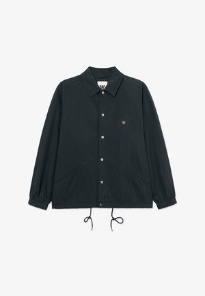 Jachetă neagră cu nasturi, guler, manșete elastice, tiv cu șnur, două buzunare laterale și o mică insignă maro cu logo pe piept.