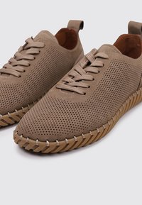 Baskets perforées beige avec des bouts ronds, des lacets assortis et des semelles en caoutchouc texturé présentant une couture en zigzag sur le bord.