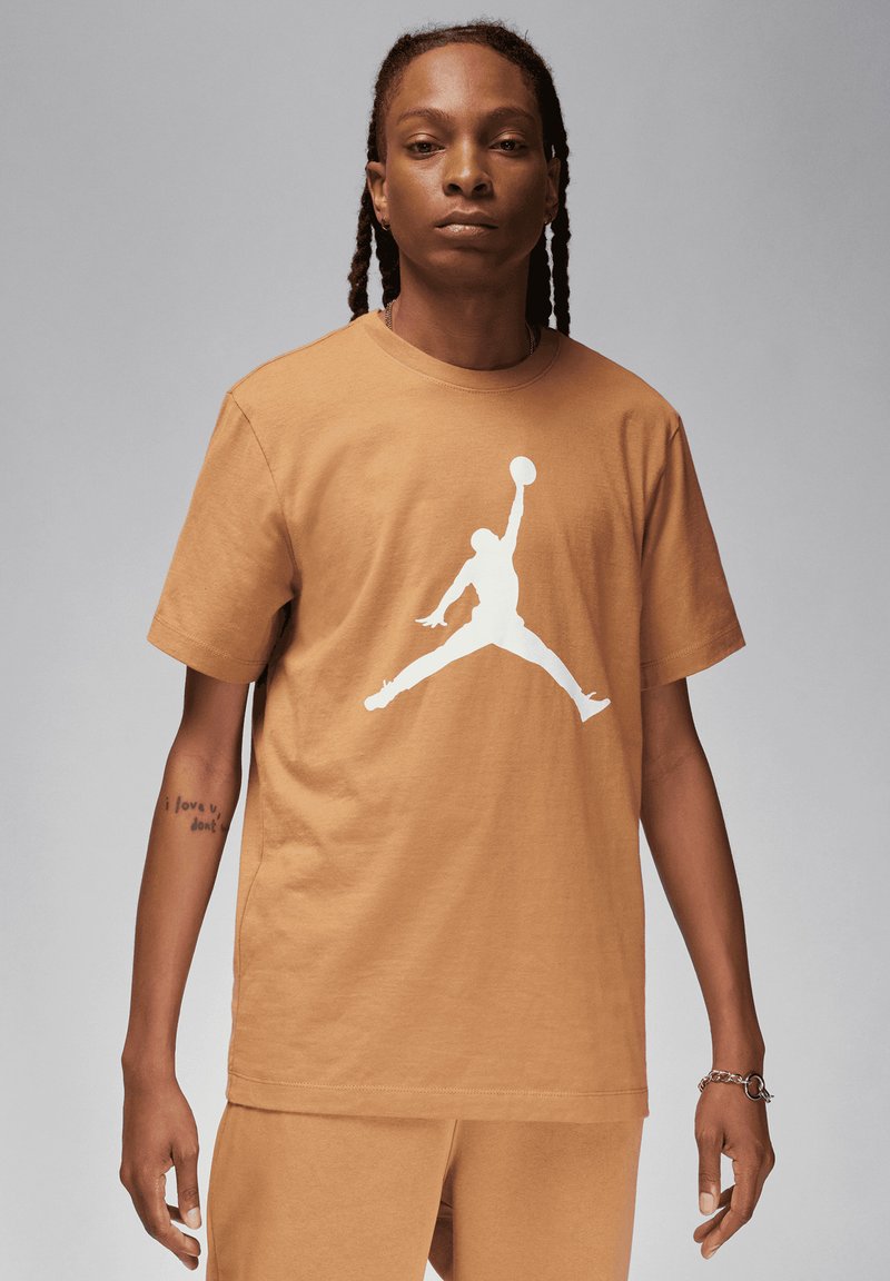 T-shirt in cotone marrone con un grande logo Jumpman bianco. Il collo rotondo e le maniche corte completano la sua vestibilità rilassata.