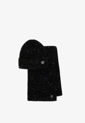 Conjunto de gorro y bufanda tejidos en negro con textura acanalada y motas blancas. La bufanda tiene una etiqueta con el logo, ambos hechos de un material cálido y acogedor.