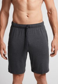 Grå atletiska shorts med dragsko i midjan, tillverkade av mjukt material, med en avslappnad passform och utan synliga mönster eller dekorationer.