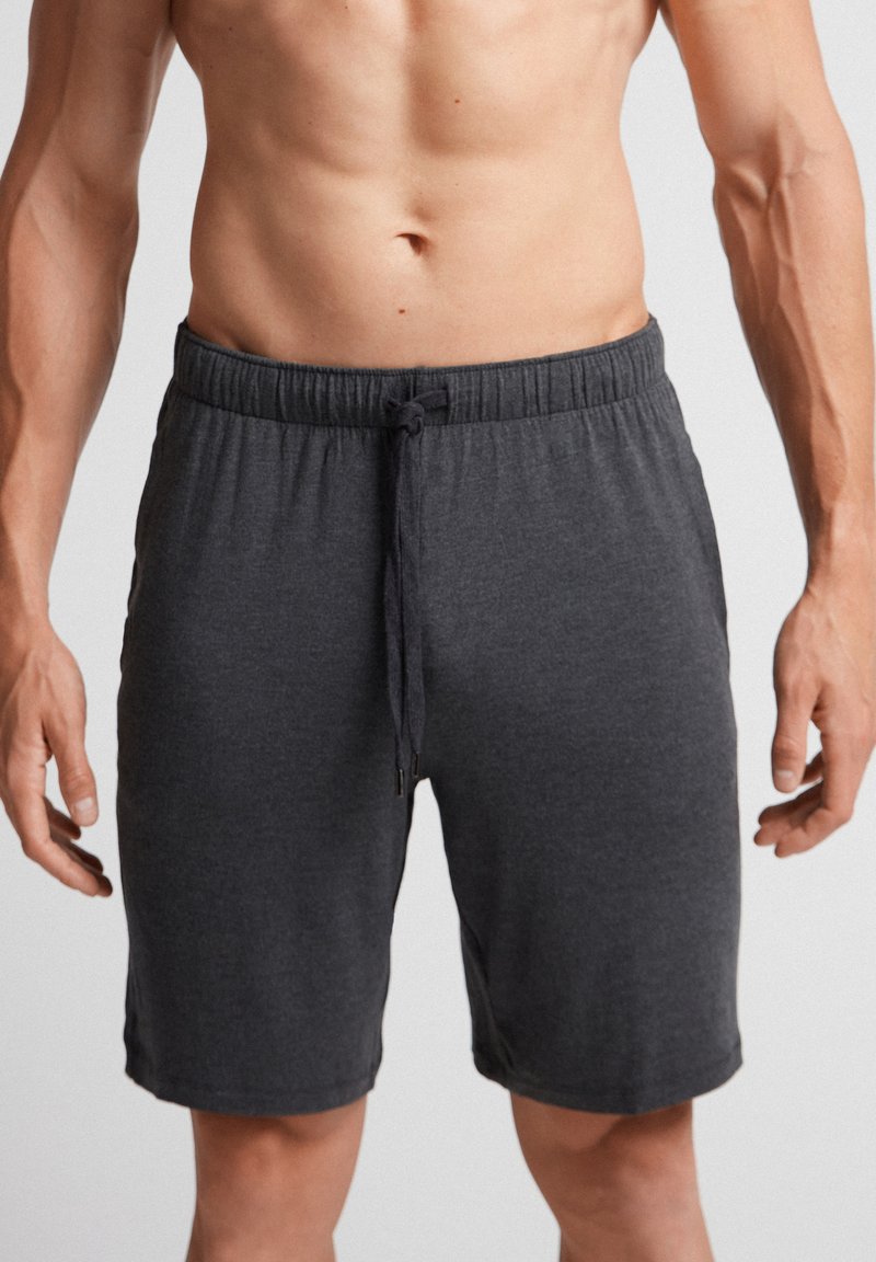 Grå atletiska shorts med dragsko i midjan, tillverkade av mjukt material, med en avslappnad passform och utan synliga mönster eller dekorationer.