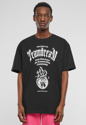 Svart t-skjorte med fet hvit teksttrykk og et grafisk bilde av en basketball med flammer under. Korte ermer, avslappet passform.