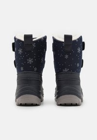 Bottes de neige en tissu navy avec des motifs de flocons de neige blancs, deux sangles ajustables et une semelle en caoutchouc grise avec un profil texturé pour une meilleure adhérence.