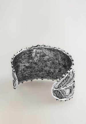 Silver cuff bracelet featuring a textured surface, leaf motif accents, and rounded edges with small decorative beads along the rim.