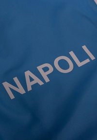 Blauwe stof met opvallende, witte letters die "NAPOLI" spellen. Het materiaal lijkt glad te zijn met een lichte glans en een kreukelstructuur.