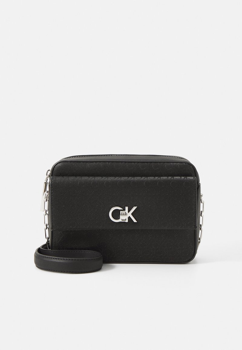 Borsa a tracolla sintetica nera con texture, dotata di hardware argentato, chiusura zip e logo prominente sul davanti. Inclusa tracolla regolabile.
