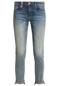 Vaqueros de mezclilla azul claro con un diseño ajustado, que cuentan con un dobladillo desgastado decorado con tachuelas y un estilo clásico de cinco bolsillos.