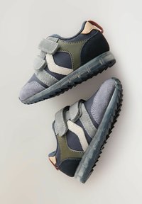 Blå og grå atletik sko med en blanding af materialer, herunder mesh og ruskind. Designet med velcro-remme og en gennemsigtig sål.