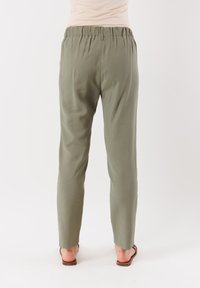Pantaloni leggeri, verde oliva, a gamba affusolata con vita elastica e una superficie liscia. Presentano una vestibilità rilassata e un design minimale.