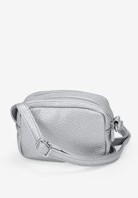 Bolso cruzado de cuero plateado con un acabado texturizado, que cuenta con un cierre de cremallera y una correa ajustable. Forma rectangular compacta.