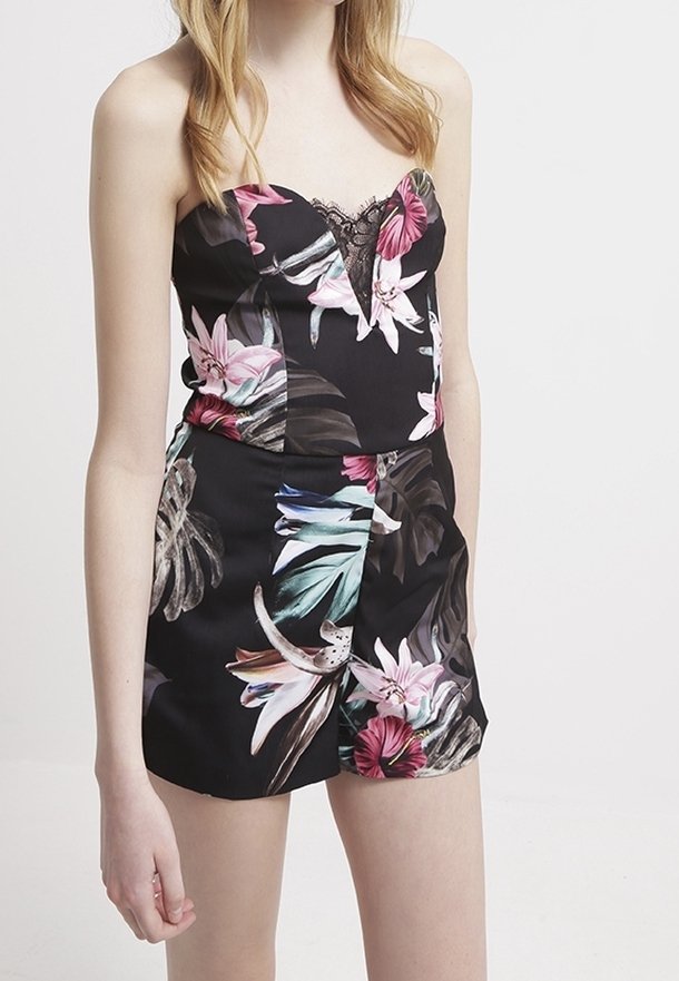 Černý květinový overal s výstřihem do srdce, krajkovými detaily a živými tropickými vzory v růžové, zelené a bílé. Hladká tkanina, krátký střih.