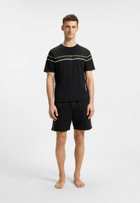 Black short-sleeve t-shirt with horizontal white and gold stripes and logo; paired with black shorts featuring gold side stripes.